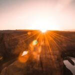 Captivating sunrise over Horseshoe Bend with sun rays illuminating the desert landscape.